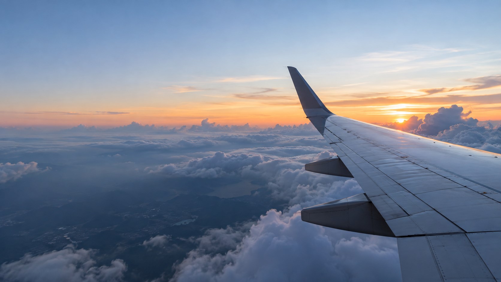 An aircraft wing above the clouds at dawn